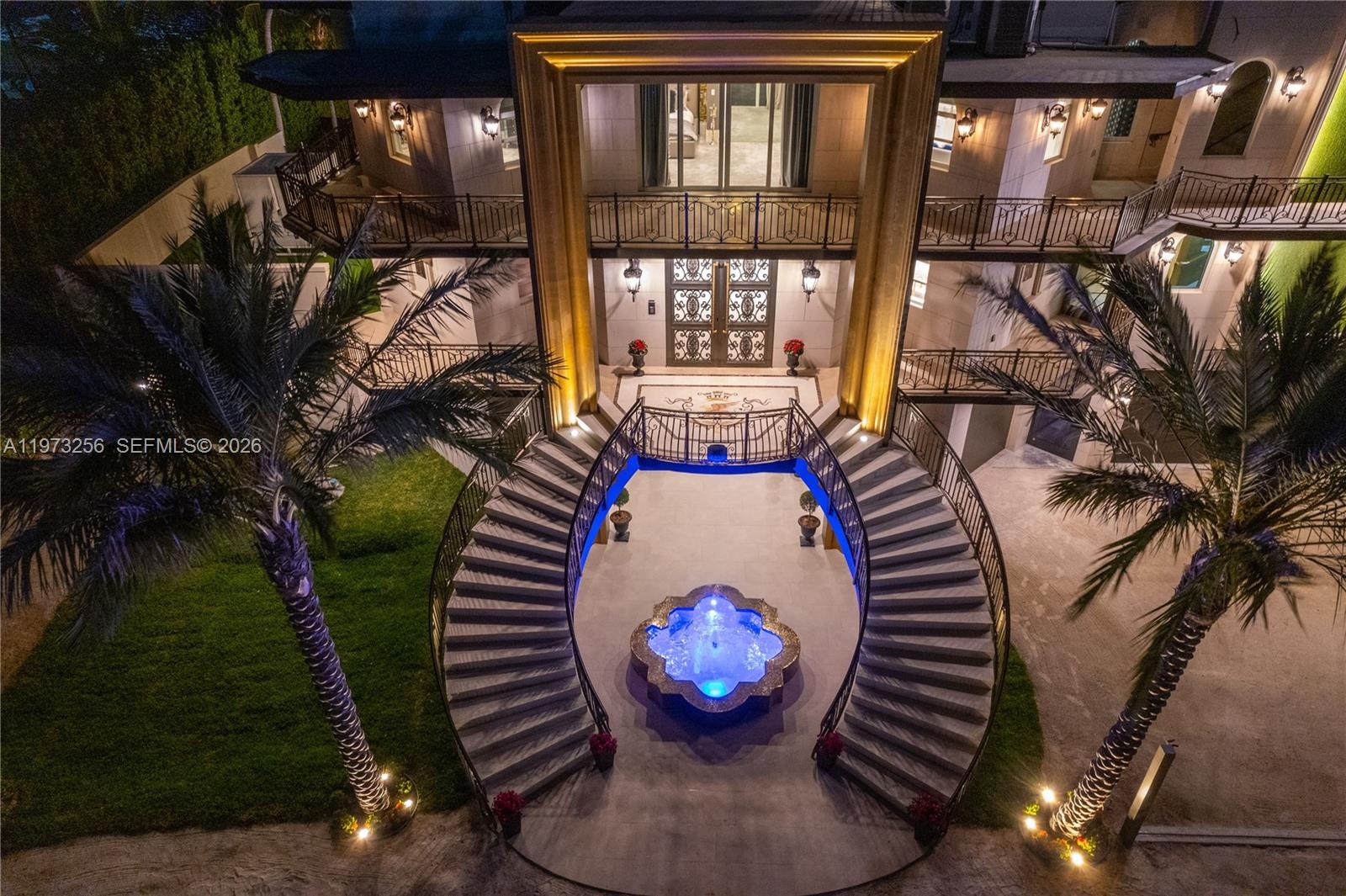 Grand entrance staircase with illuminated fountain and palm trees